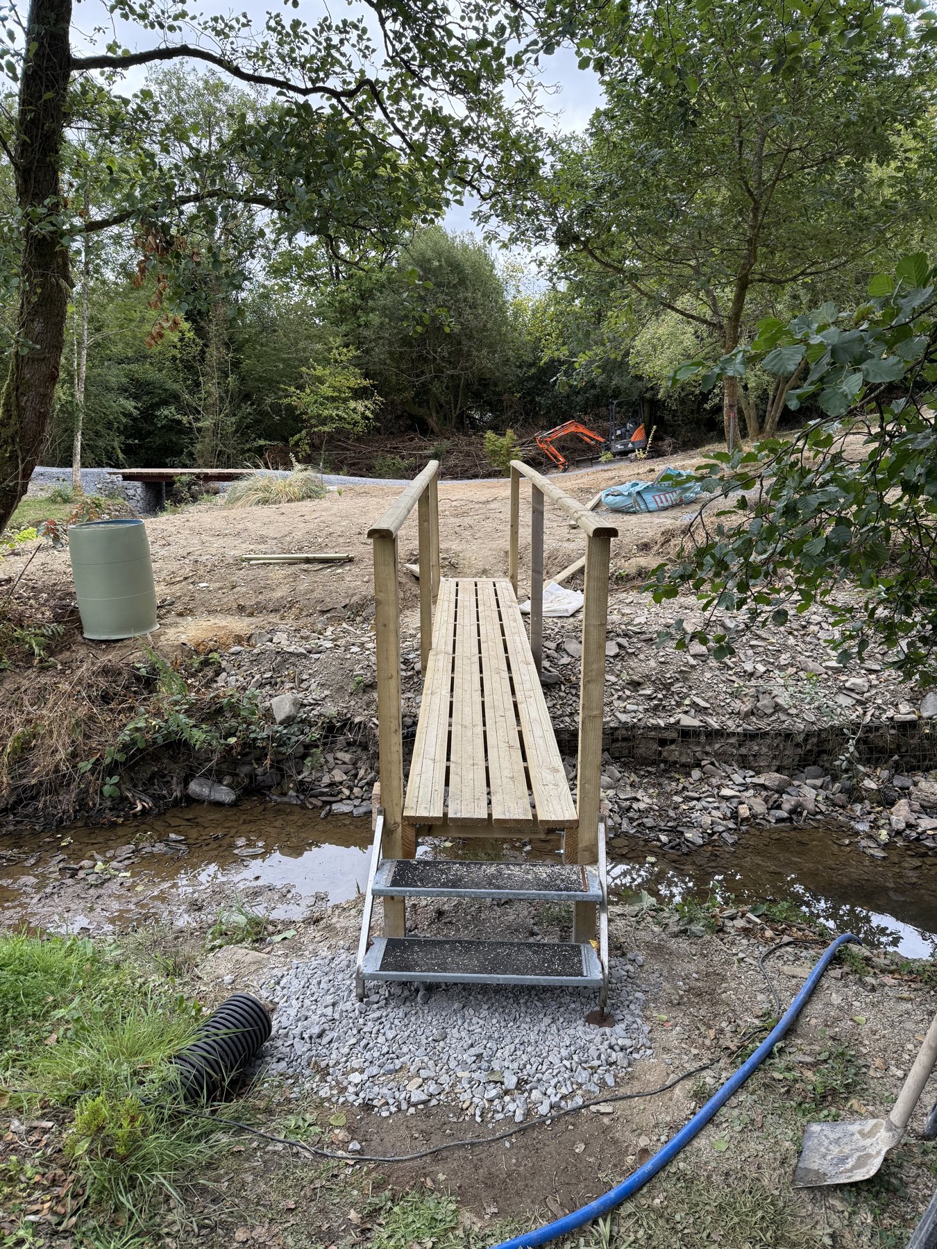 Timber footbridge with handrails surrounded by rural vegetation