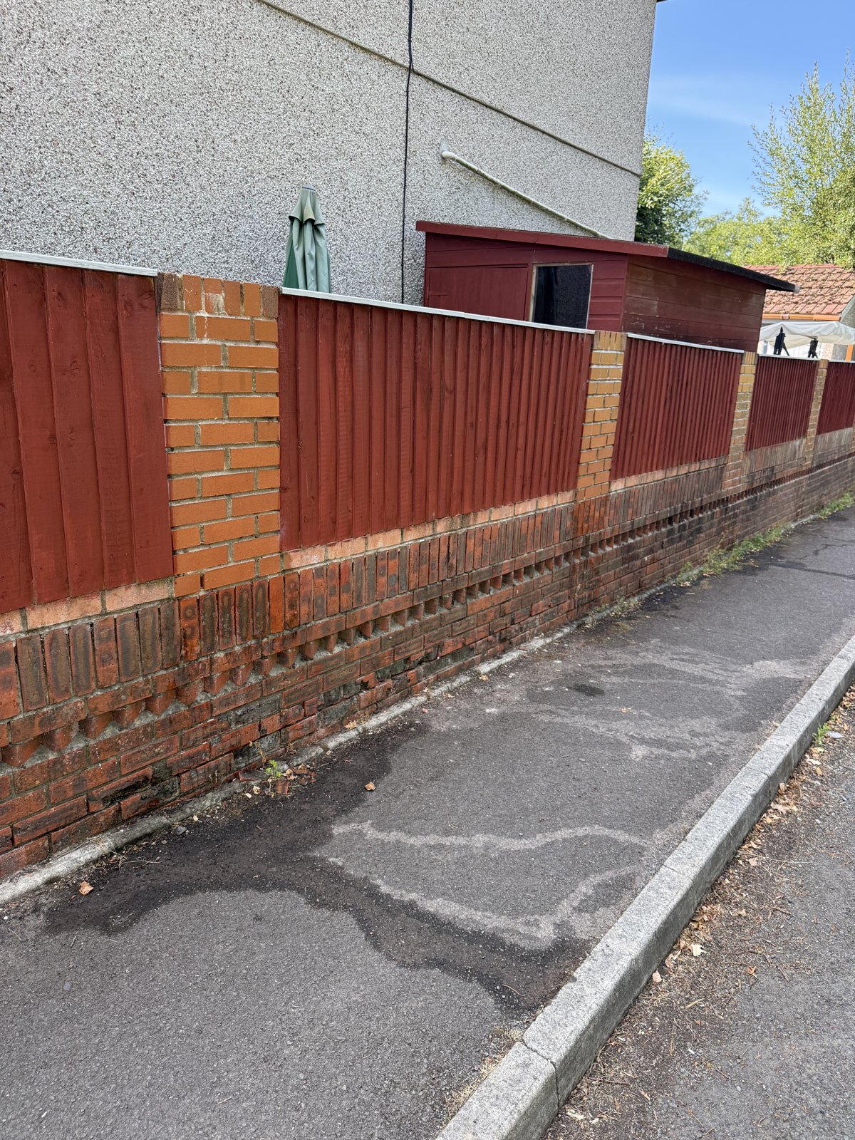 Wider view of brick boundary wall and red timber fence